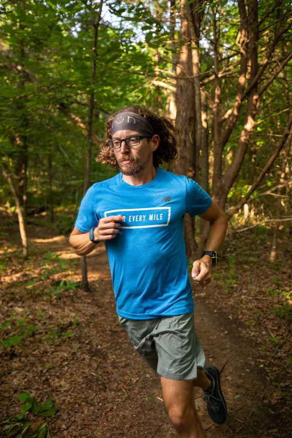 man wearing blue shirt trail running in the forest