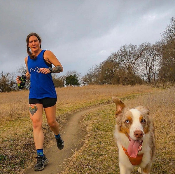 woman trail running with her dog